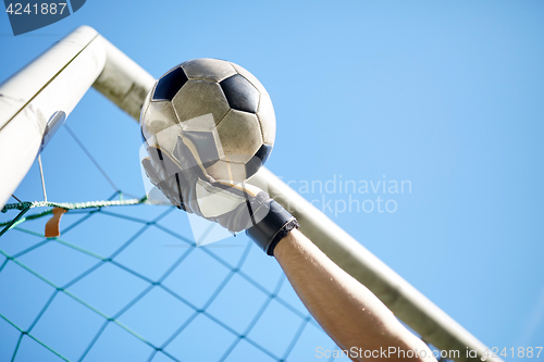 Image of goalkeeper with ball at football goal over sky