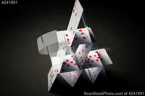 Image of house of playing cards over black background