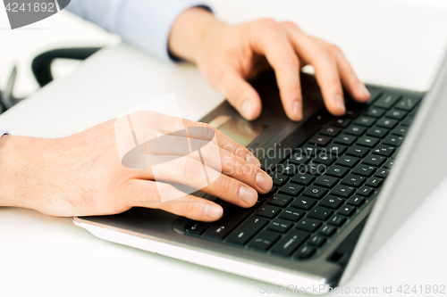 Image of close up of male hands with laptop typing