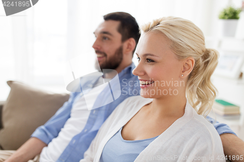 Image of smiling happy couple sitting on sofa at home