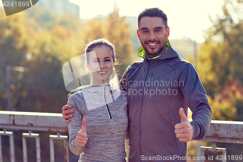 Image of smiling couple showing thumbs up outdoors