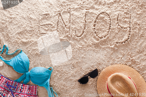 Image of Enjoy written in a sandy tropical beach