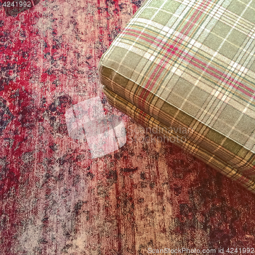 Image of Checked textile hassock on a red carpet