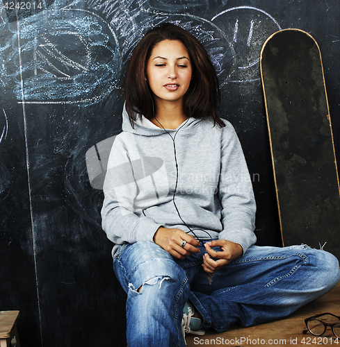 Image of young cute teenage girl in classroom at blackboard seating on ta