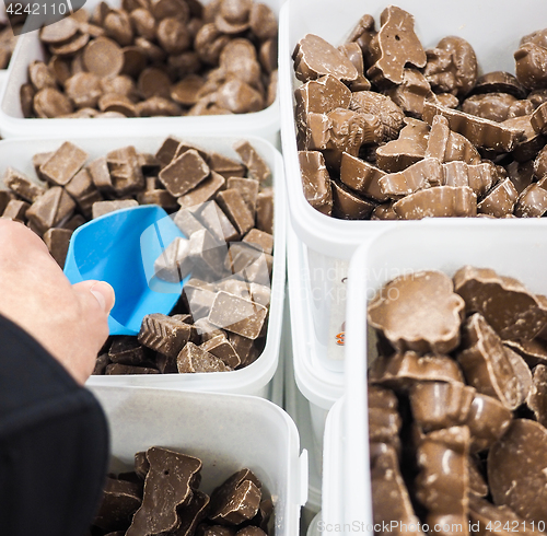 Image of Unrecognizable person scooping assorted pieces of chocolate with