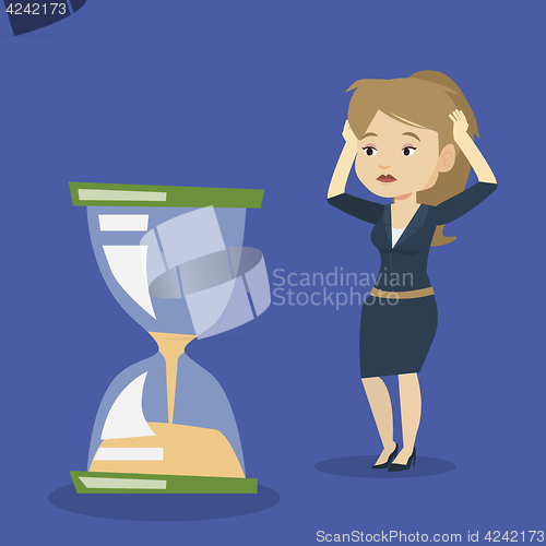 Image of Desperate business woman looking at hourglass.