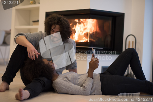 Image of multiethnic couple using tablet computer on the floor