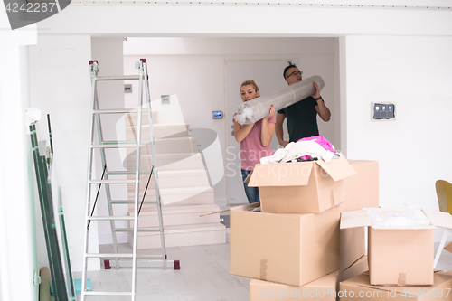 Image of couple carrying a carpet moving in to new home