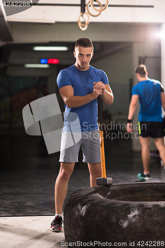 Image of man workout with hammer and tractor tire