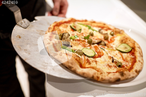 Image of chef placing pizza from peel to plate at pizzeria