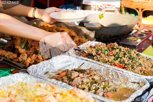 Image of seller with rice and wok food at street market