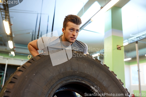 Image of man doing strongman tire flip training in gym