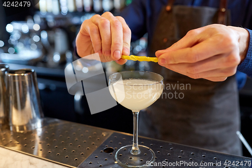 Image of bartender with glass of cocktail and lemon at bar