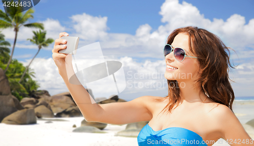 Image of woman in swimsuit taking selfie with smatphone