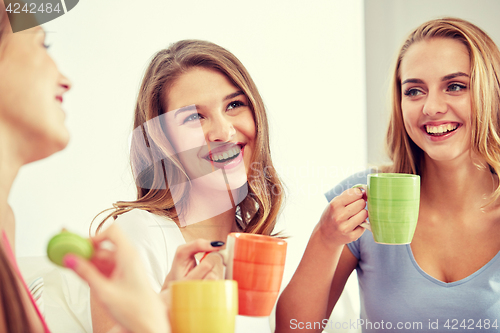 Image of happy young women drinking tea with sweets at home