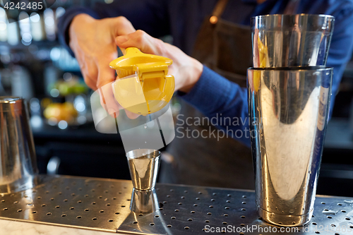 Image of bartender squeezing juice into jigger at bar