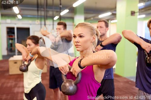 Image of group of people with kettlebells exercising in gym