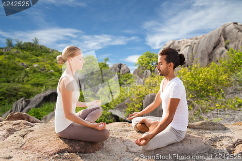 Image of happy couple doing yoga and meditating outdoors