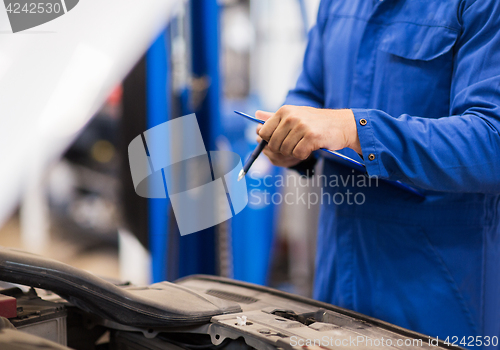 Image of auto mechanic man with clipboard at car workshop