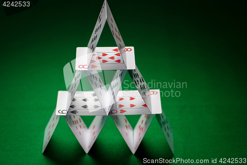 Image of house of playing cards on green table cloth