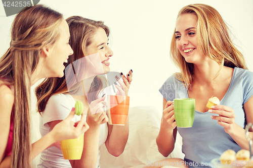 Image of happy young women drinking tea with sweets at home