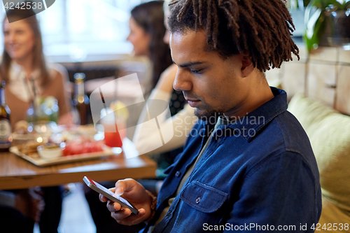 Image of man with smartphone and friends at restaurant