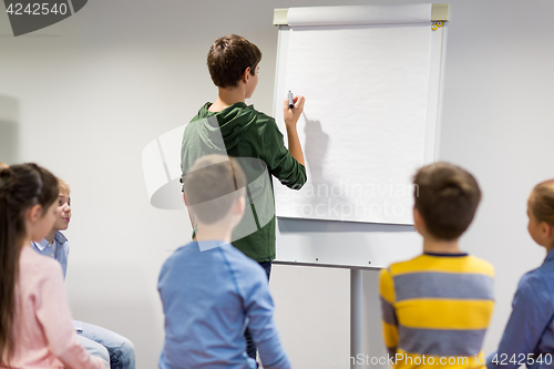 Image of student boy with marker writing on flip board