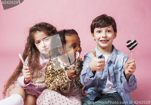 Image of lifestyle people concept: diverse nation children playing together, caucasian boy with african little girl holding candy happy smiling 