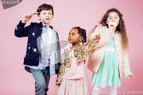 Image of lifestyle people concept: diverse nation children playing together, caucasian boy with african little girl holding candy happy smiling closeup