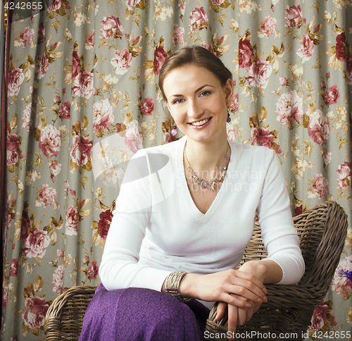 Image of pretty mature woman happy smiling sitting in room interior, life