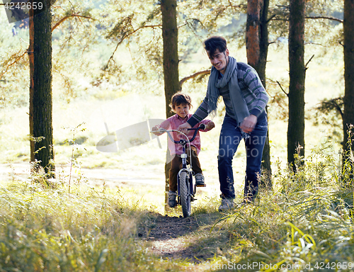 Image of father learning his son to ride on bicycle outside, real happy f