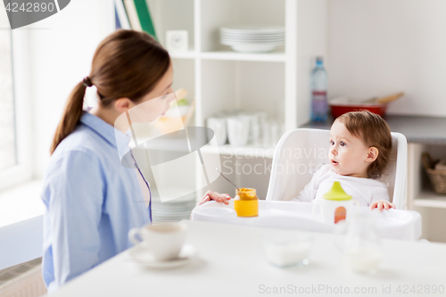Image of happy mother and baby having breakfast at home