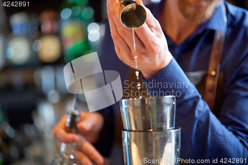 Image of bartender with shaker preparing cocktail at bar