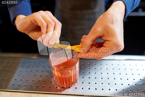 Image of bartender with glass of cocktail and orange peel