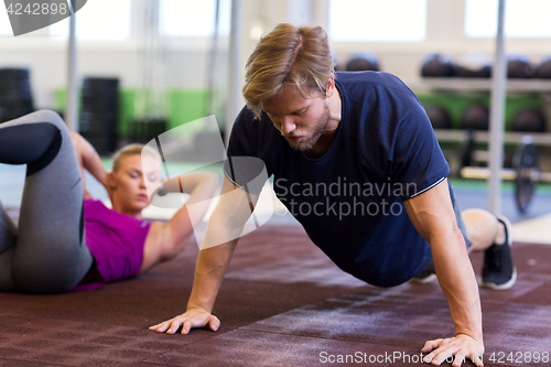 Image of man exercising and doing straight arm plank in gym