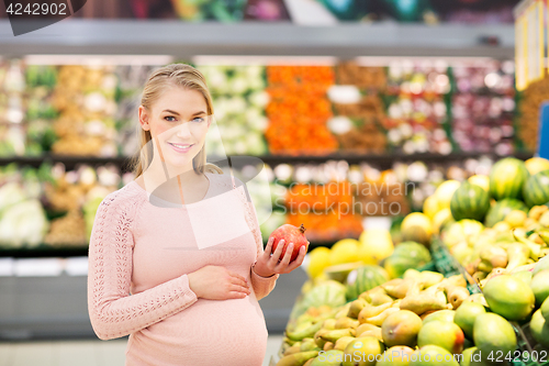 Image of happy pregnant woman with pomegranate at grocery