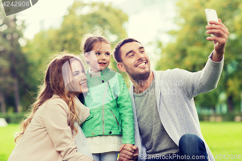 Image of happy family taking selfie by smartphone outdoors