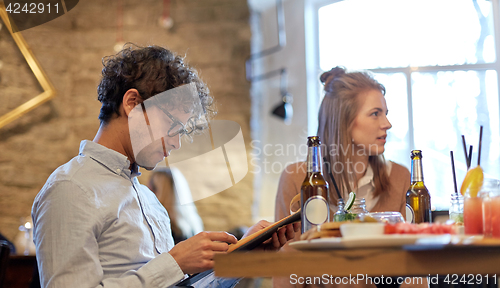 Image of happy friends looking to menu at restaurant