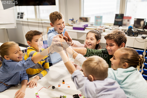 Image of happy children making high five at robotics school