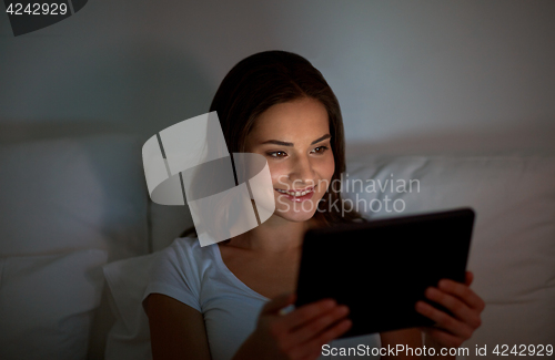 Image of young woman with tablet pc in bed at home bedroom