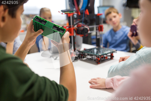 Image of kids with 3d printer part at robotics school