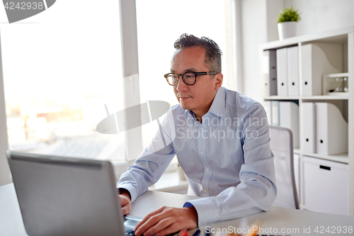 Image of businessman in eyeglasses with laptop office