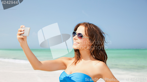 Image of woman in swimsuit taking selfie with smatphone