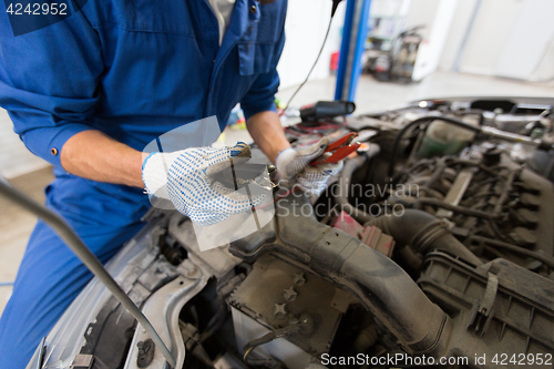 Image of auto mechanic man with cleats charging battery