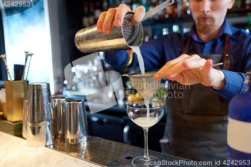 Image of bartender with shaker preparing cocktail at bar