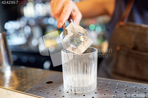 Image of bartender adding ice cube into glass at bar