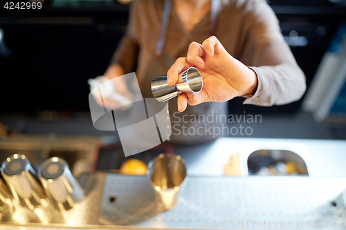 Image of bartender with cocktail shaker and jigger at bar