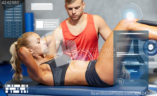 Image of woman with personal trainer doing sit ups in gym