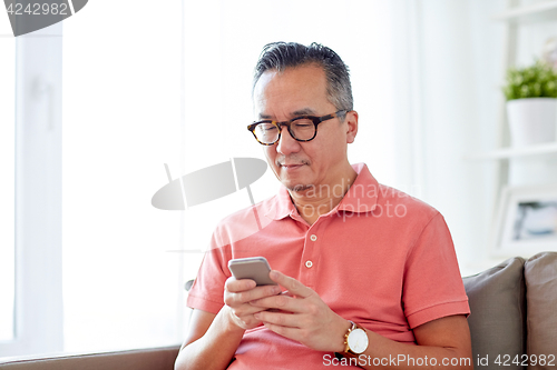 Image of man with smartphone sitting on sofa at home