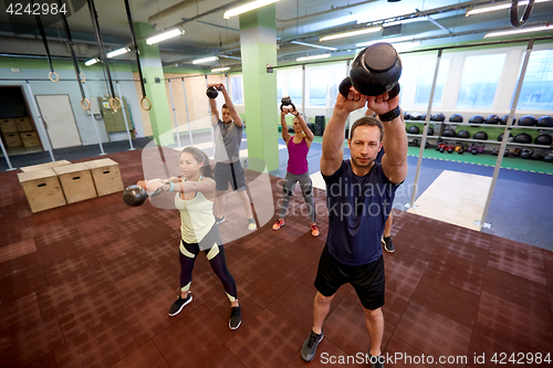 Image of group of people with kettlebells exercising in gym